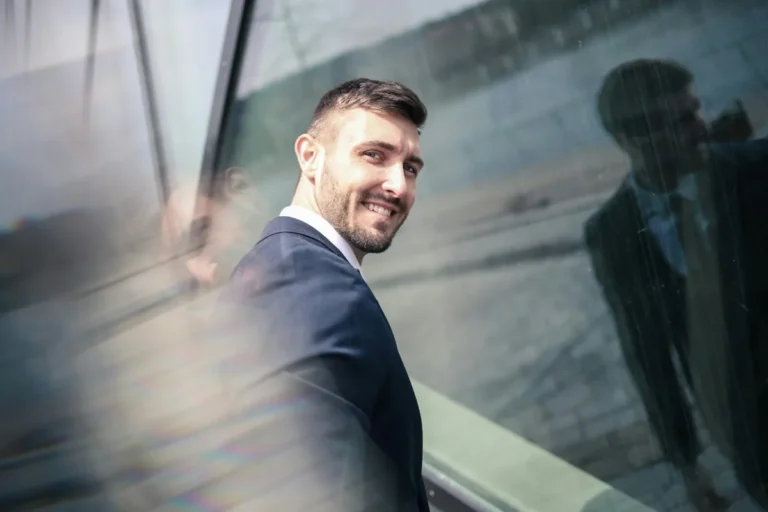 Smiling professional in a suit walking past a glass building