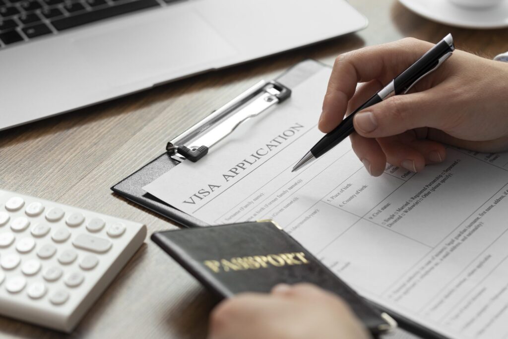 Person completing a Thailand visa application form at a desk with passport and calculator