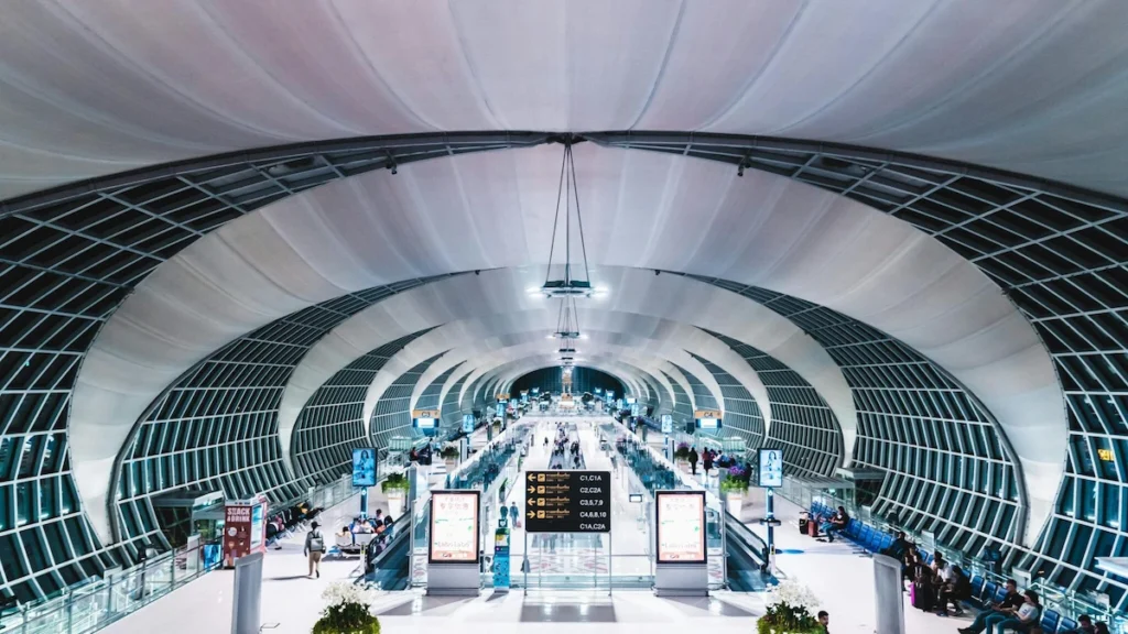 Interior view of Suvarnabhumi Airport departure hall with travelers walking through security and check-in area in Thailand