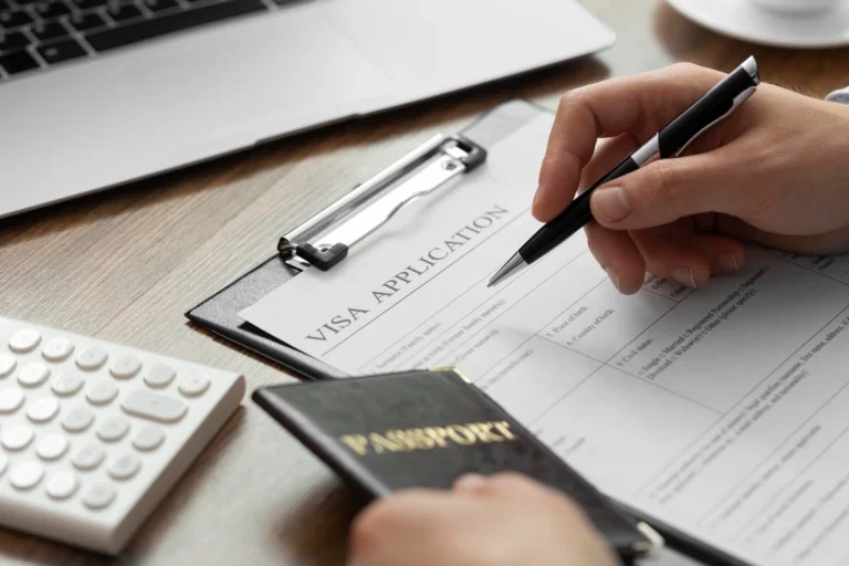 Person filling out a Thailand visa application form with passport on a desk