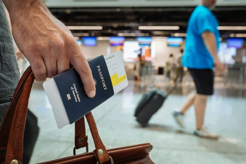Traveler holding a passport and boarding pass in a busy airport terminal