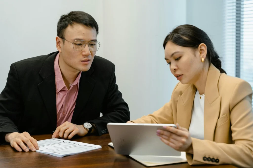 Thai business consultant explaining BOI company requirements on a tablet to a foreign investor