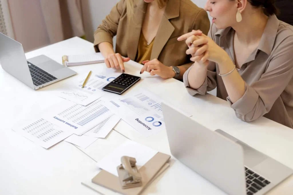 Business advisor showing BOI qualification details on a tablet to a foreign entrepreneur in an office setting.