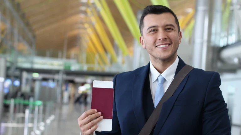 Business traveler smiling at the airport while holding passport and boarding pass before flying to Thailand