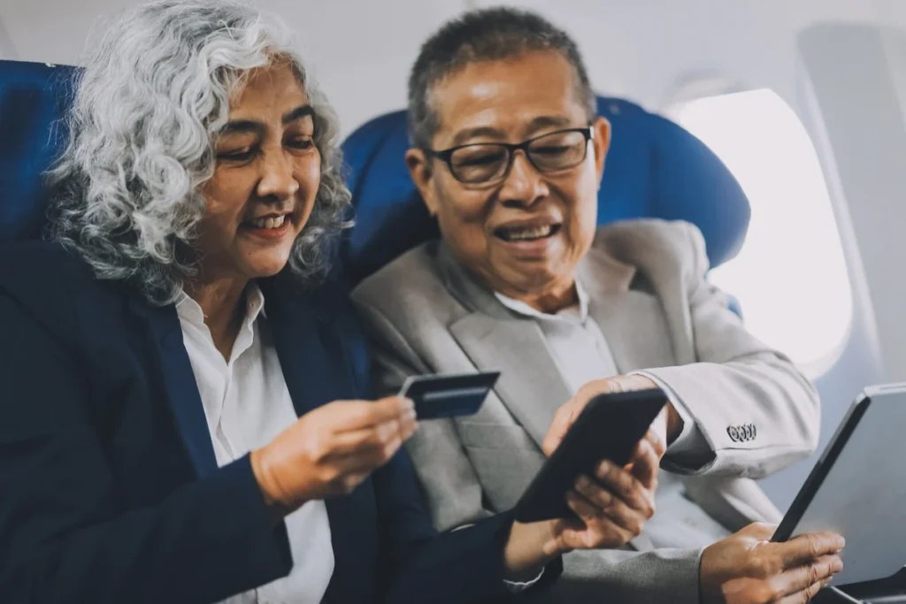 Senior couple on an airplane reviewing travel documents and payment card before their long stay in Thailand