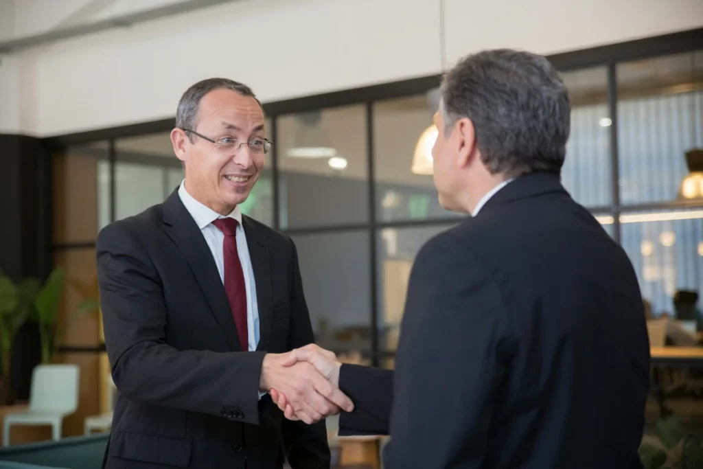 Executive greeting a foreign investor with a handshake in a modern Thai office