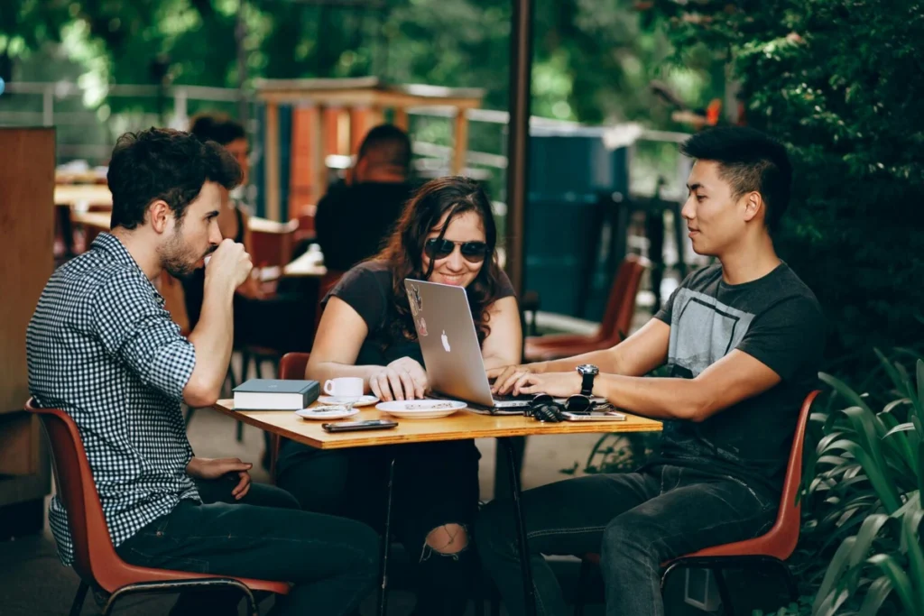 Group of young professionals working together on a laptop at an outdoor café